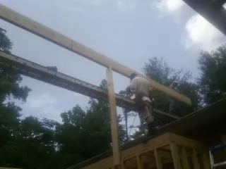 Carpenter setting a ridge beam over a new addition frame — Ice Dam Removal by Roofing Brothers in Hertford