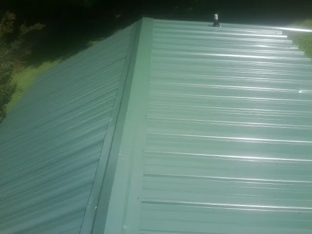New green metal panels meeting at the ridge of a roof — Flat Roof Repair work by our crew in Hertford