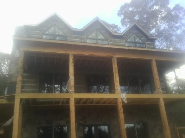 Dormers and porch framing on a large log home under construction — Roof Coating work by our crew in Hertford