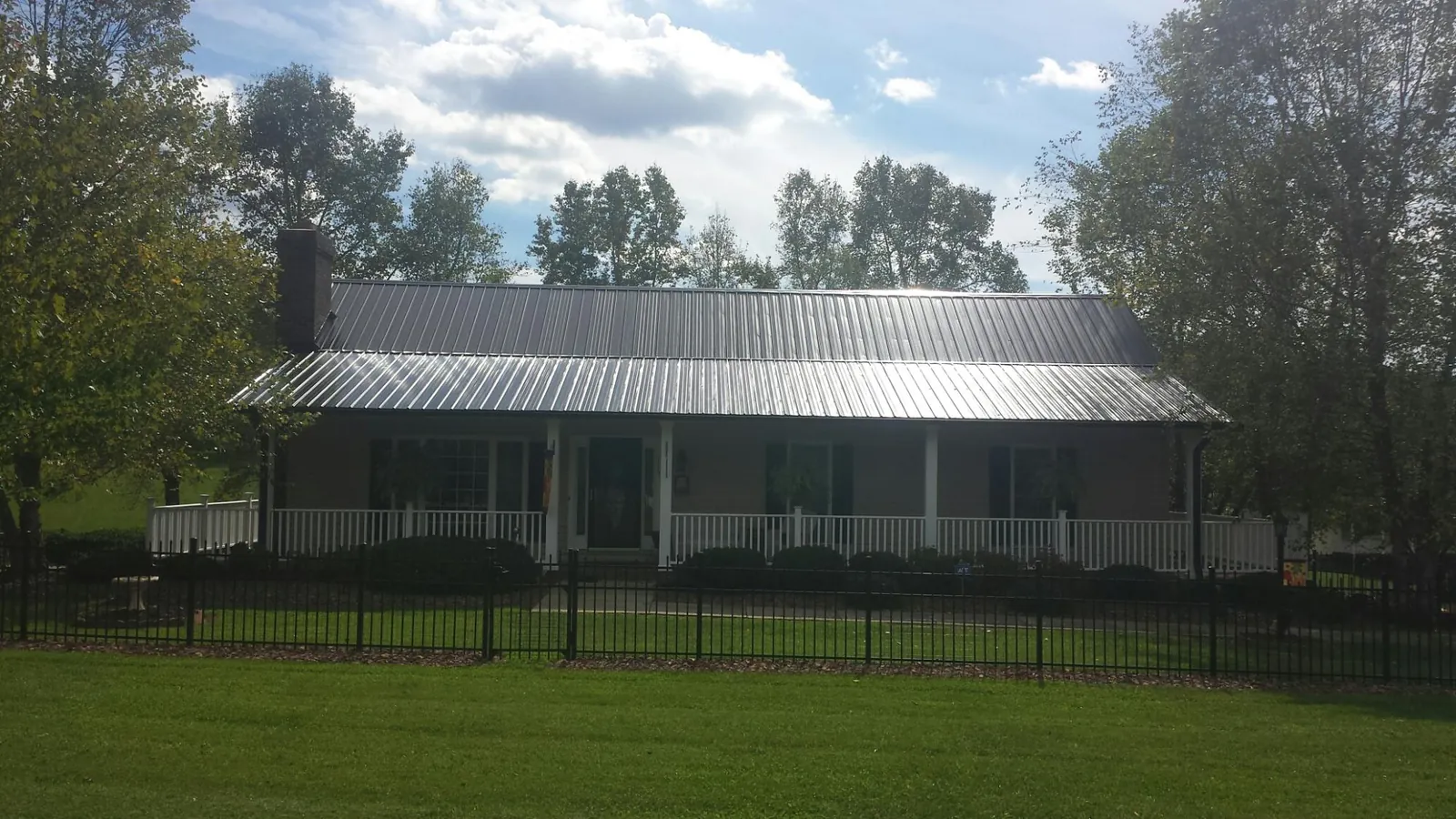 Gray metal roof on a brick ranch with a full width front porch — Gutter Guard Installation work by our crew in Hertford