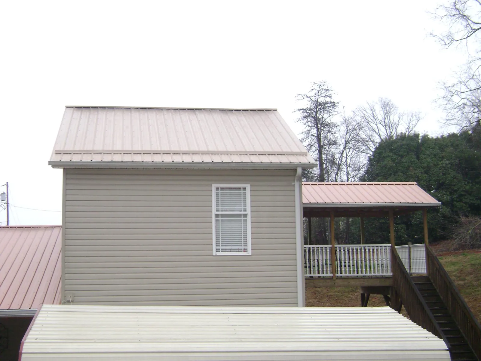 Tan metal roofs on a two story addition and attached porch in Hertford