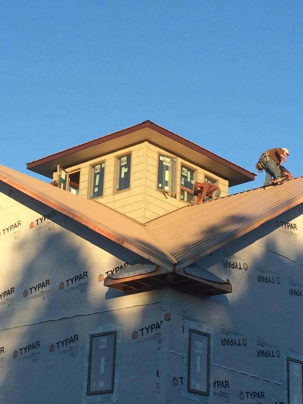 Roofers working around a rooftop cupola on a new metal roof at sunset — Roof Waterproofing in Hertford by Roofing Brothers